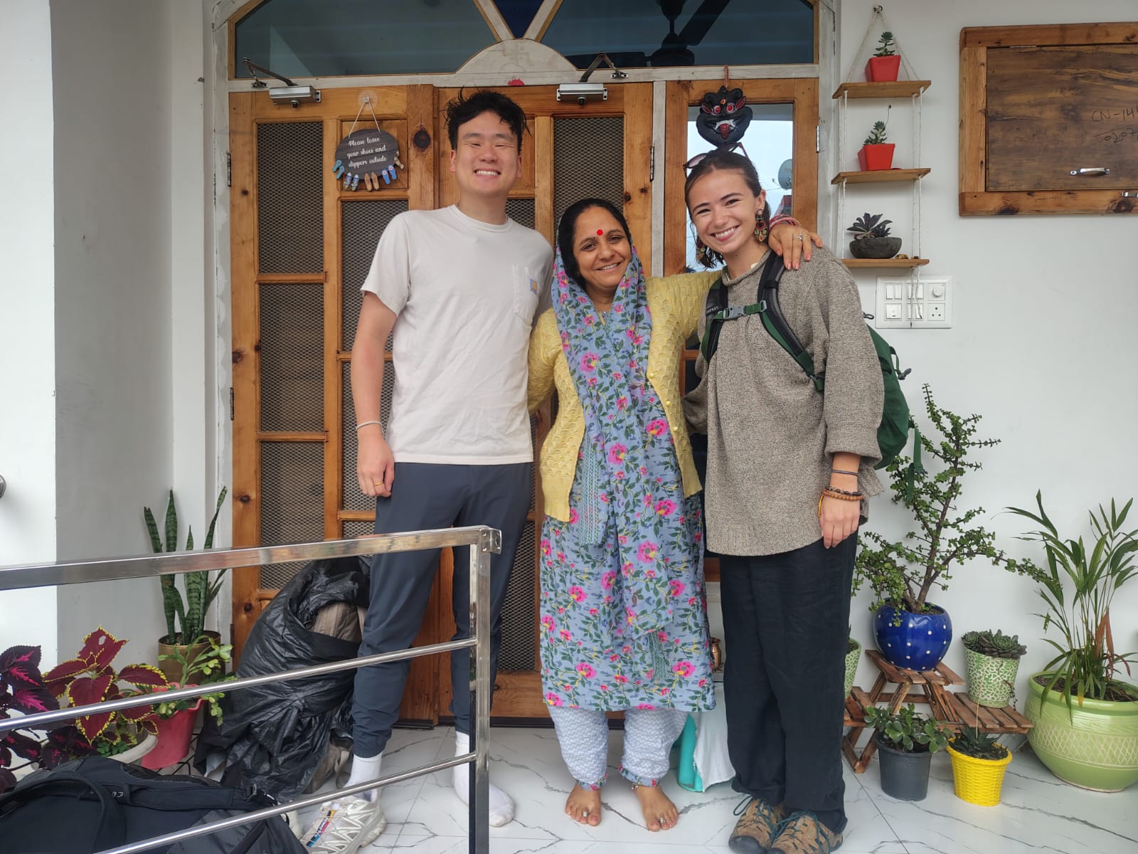 Two travellers with Bimla aunty at the dera front door before checkout